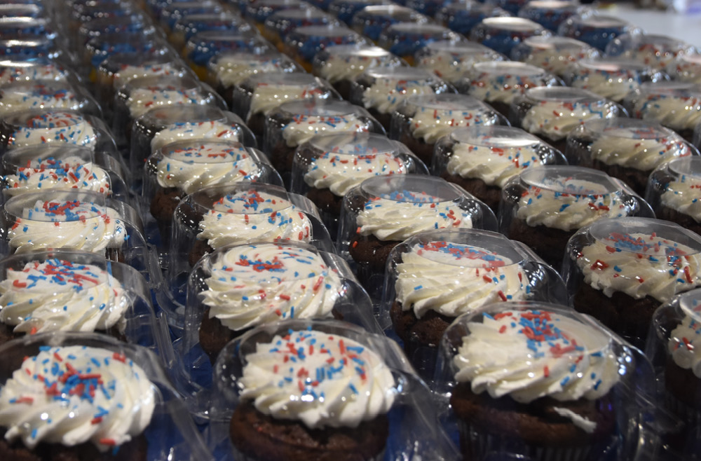 Rows of vanilla cupcakes with red and blue sprinkles in the cafeteria